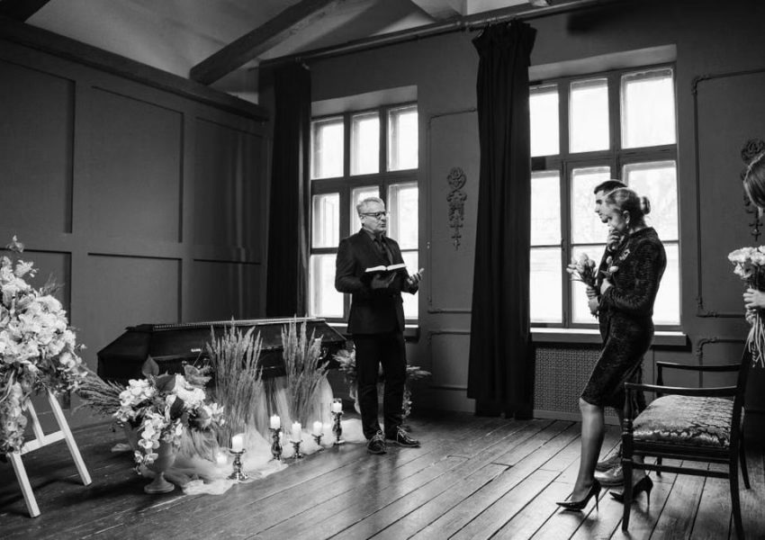 Intimate indoor funeral ceremony in grayscale, capturing solemn emotions.