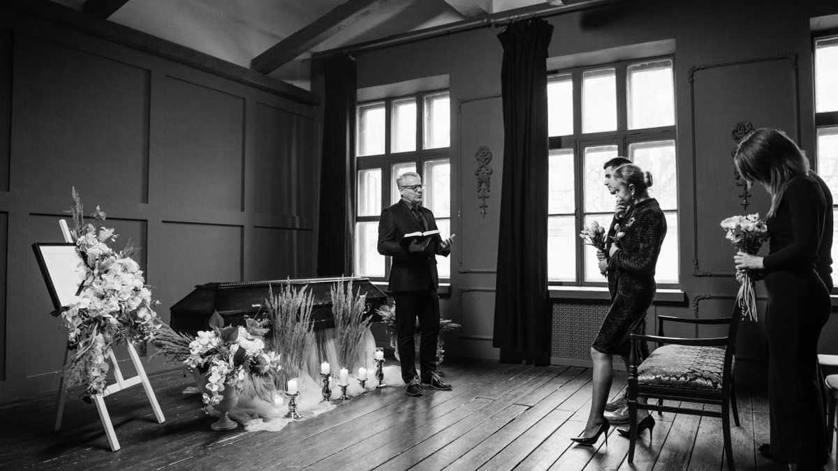 Intimate indoor funeral ceremony in grayscale, capturing solemn emotions.