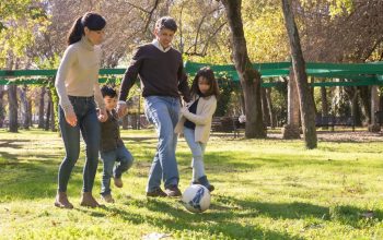A family plays soccer together in a sunny park, enjoying quality time outdoors.